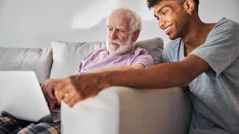 A person is looking at a laptop with an older person